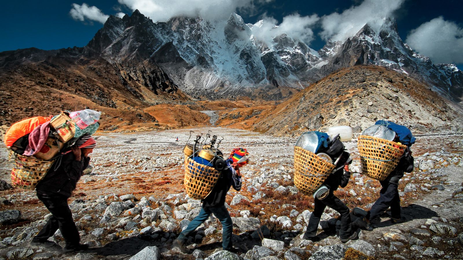 Carregadores atravessam o terreno acidentado do Himalaia, no Nepal, em grande altitude