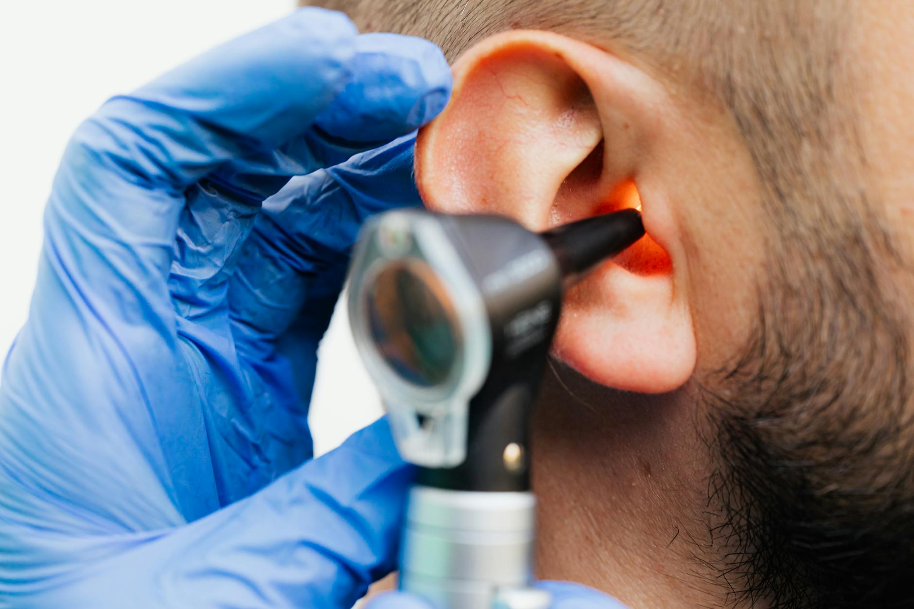 Médico examinando o ouvido de um paciente com otoscópio em ambiente clínico