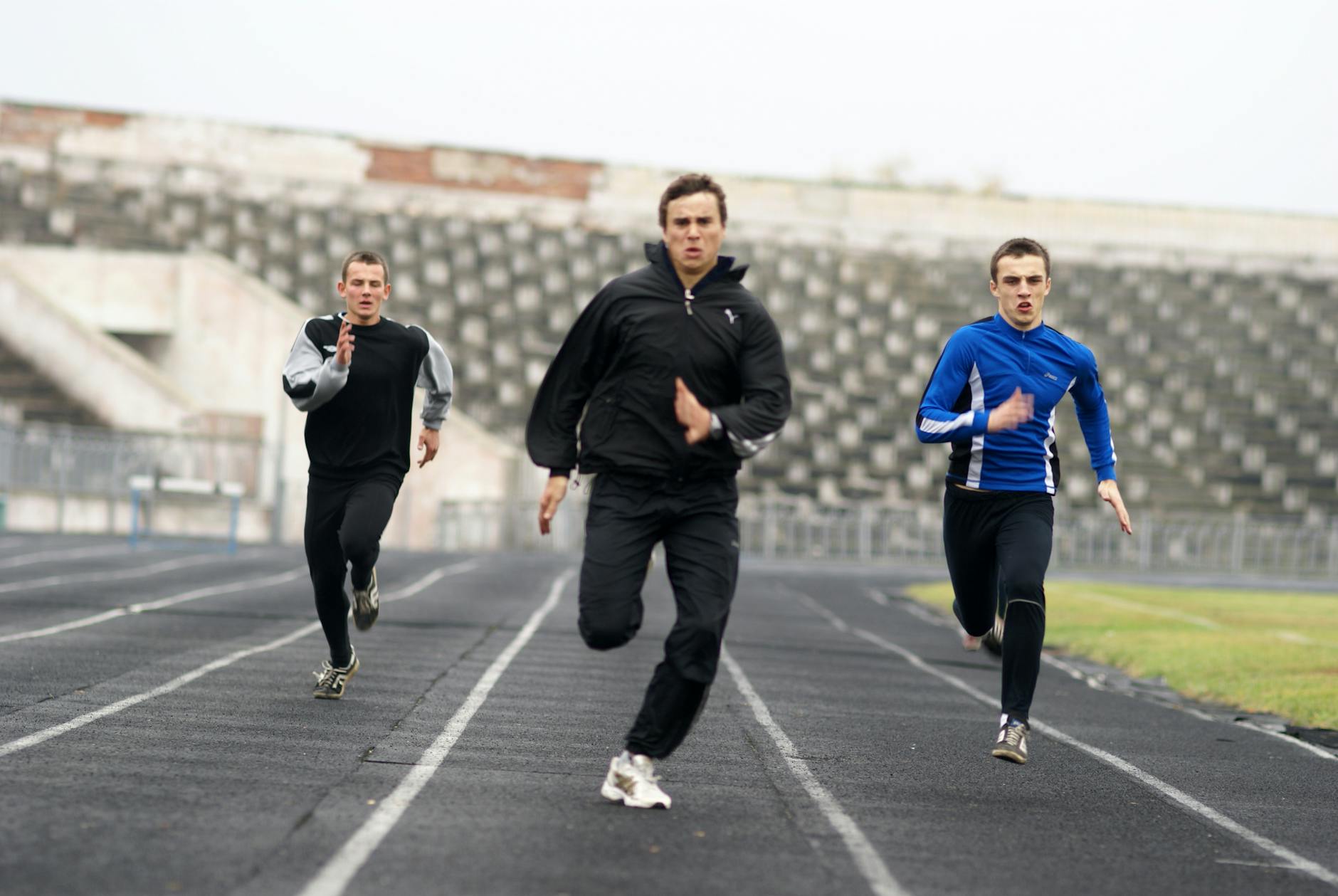 Atletas em sprint intenso em pista de atletismo, demonstrando esforço máximo característico do HIIT