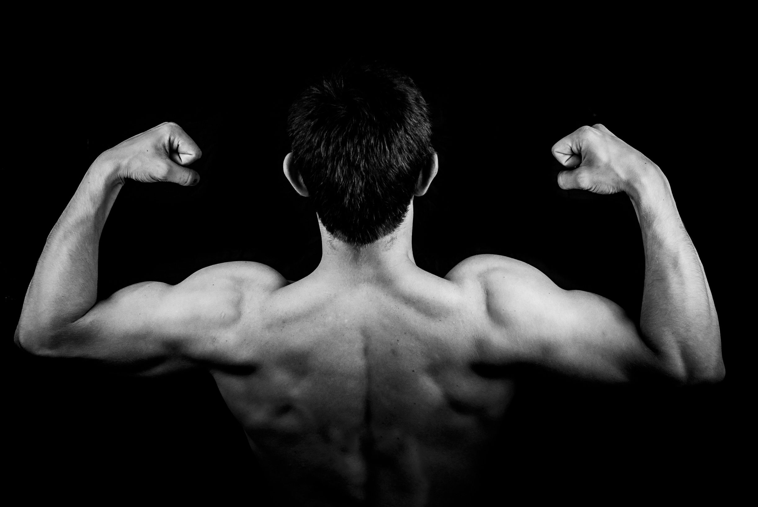 Homem com musculatura desenvolvida das costas e ombros, evidenciando hipertrofia muscular