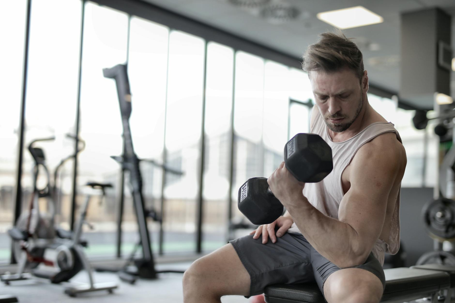 Atleta realizando treino de força com halteres em academia