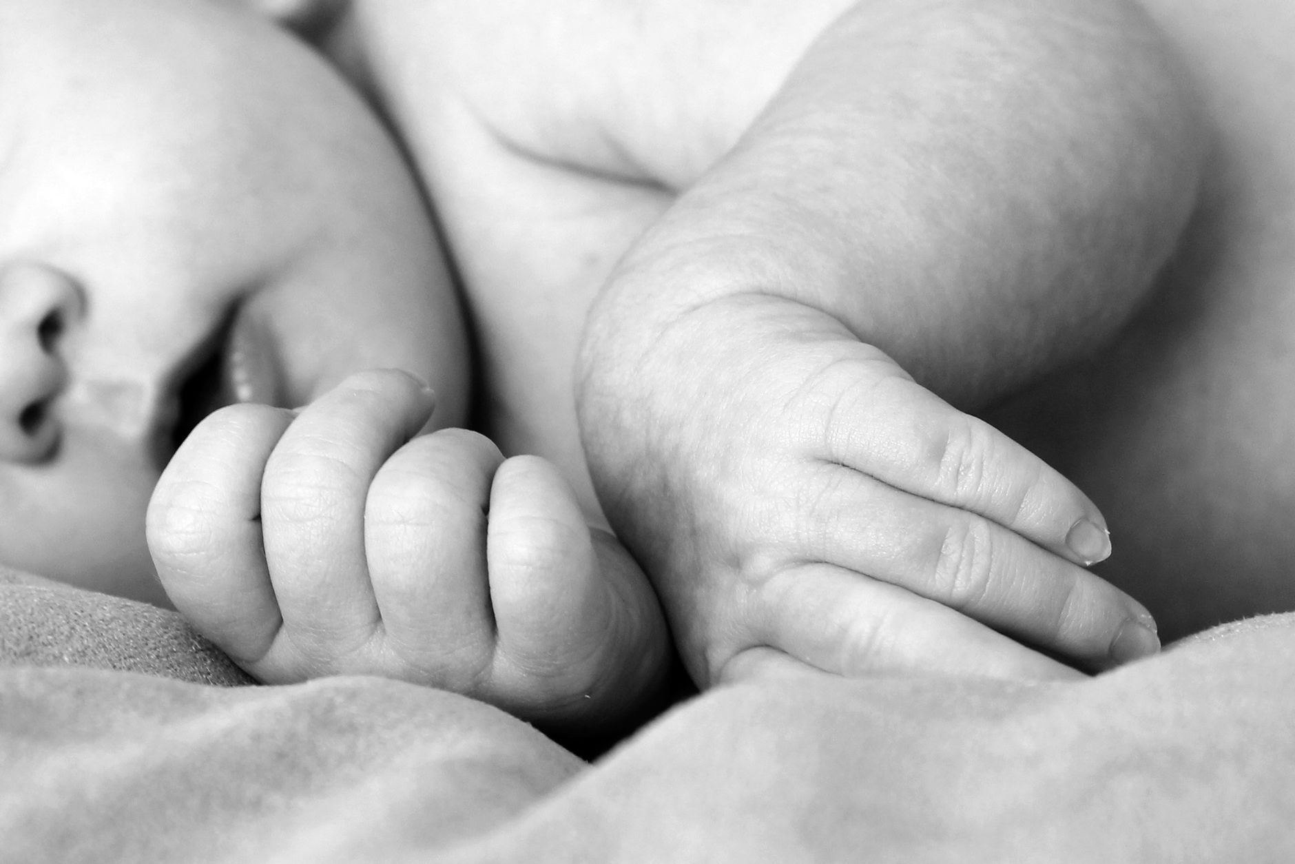 Mãozinha de um recém-nascido segurando o dedo de um adulto