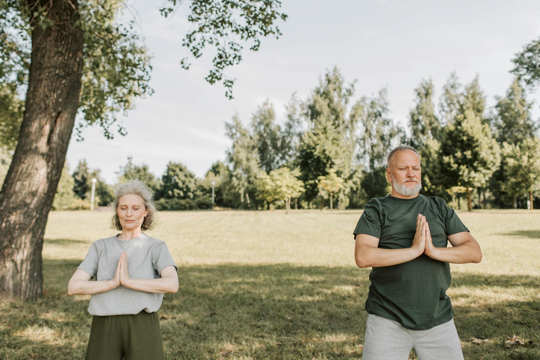Casal de idosos meditando em parque sereno, simbolizando longevidade ativa