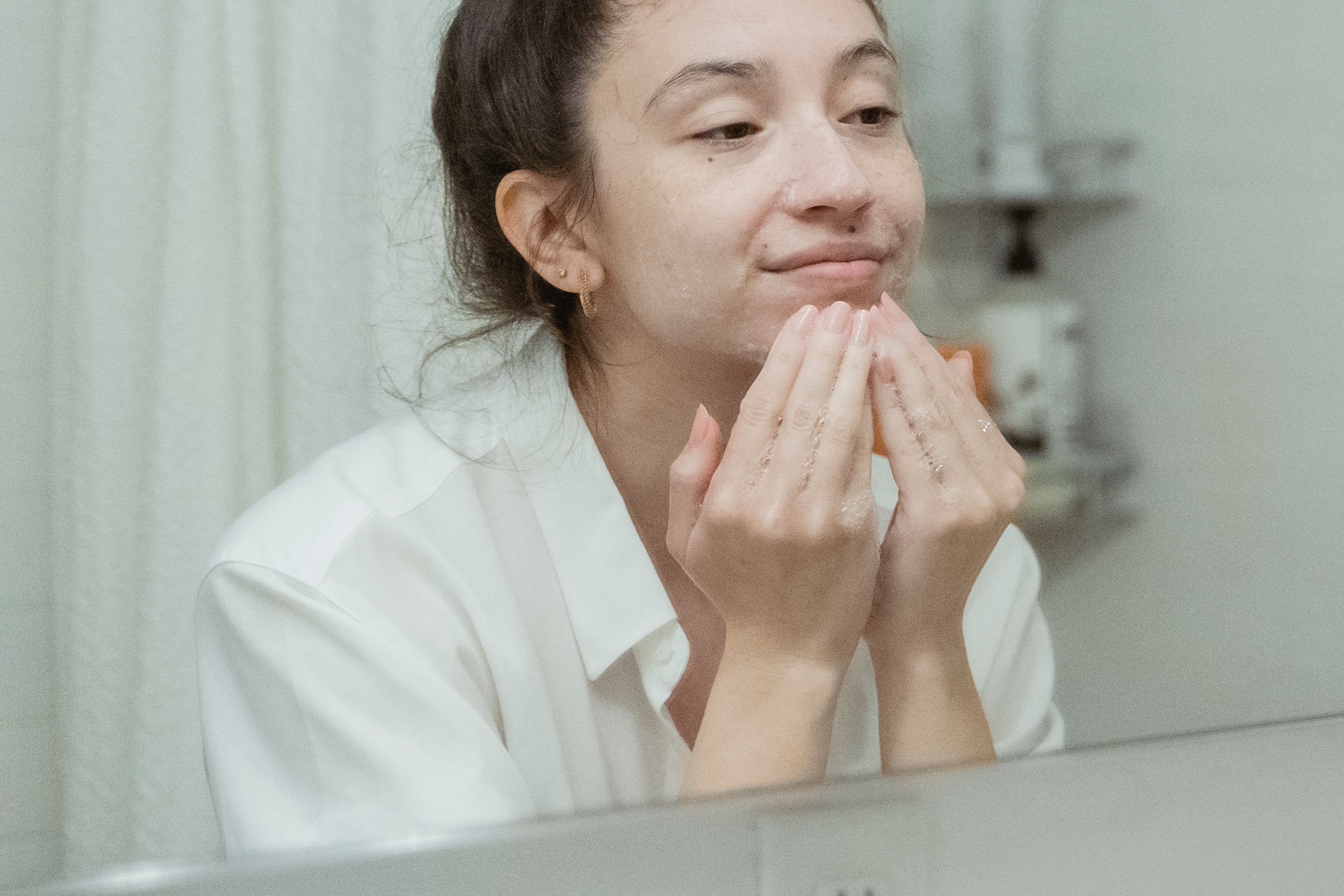 Mulher aplicando creme facial em uma rotina de cuidados suaves com a pele