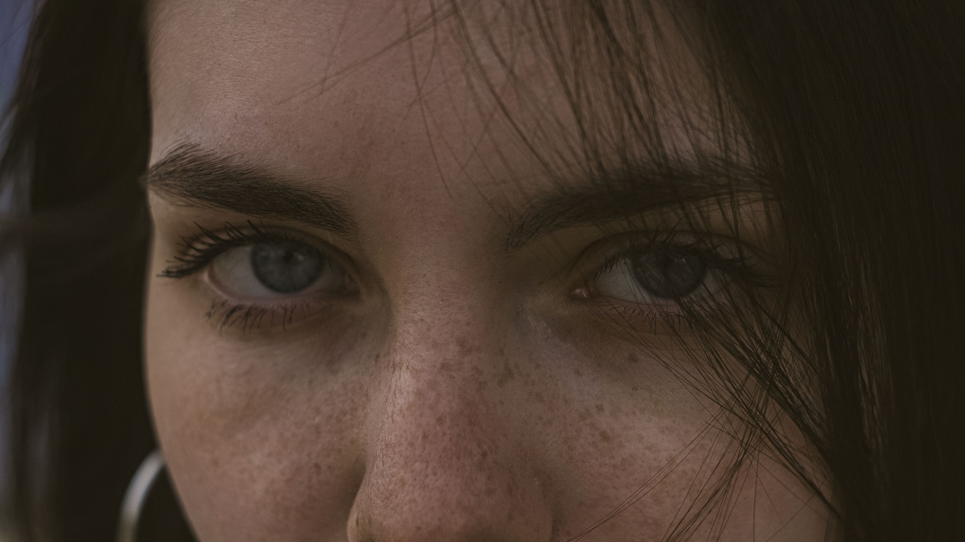 Retrato em close de um rosto humano sob luz natural, destacando a pele e o olhar