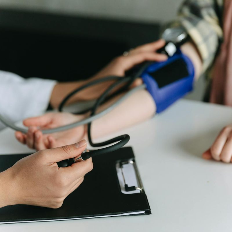 Close-up of a medical professional measuring a patient's blood pressure at a clinic.